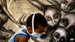 Un niño juega junto a un mural del artista Yulier P. titulado "Marcha Hacia la Oscuridad", en La Habana. (AP/Ramon Espinosa)
