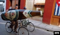 Un hombre se traslada en bicicleta con una botella de cerveza inflable..