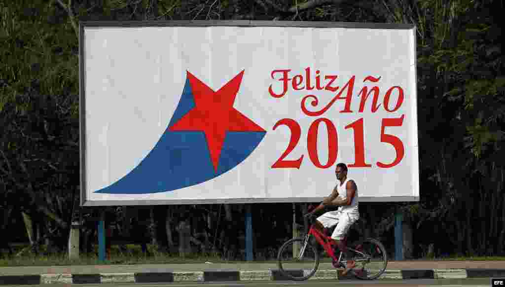 Un hombre pasa en bicicleta frente a una valla alusiva al nuevo año el miércoles 31 de diciembre de 2014, en La Habana (Cuba).