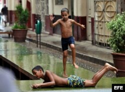 Niños juegan bajo la lluvia en La Habana.