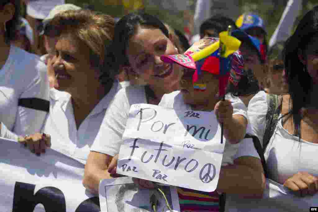 La diputada María Corina Machado sostiene una niña durante una manifestación de mujeres