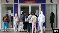Varias personas hacen fila frente a una oficina de la empresa estatal cubana ETECSA.