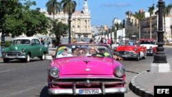 Turistas pasean por La Habana en un auto clásico. 