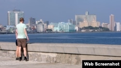 Turistas caminan frente al mar en La Habana.
