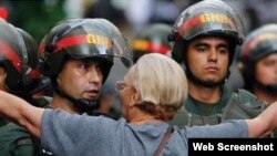 Una mujer venezolana trata de impedir el avance de agentes de la Guardia Nacional Bolivariana.