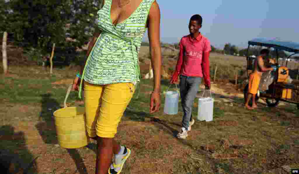 Varias personas que cargan cubos de agua en la provincia de Ciego de Ávila, una de las más afectadas por la intensa sequía que golpea a la isla.