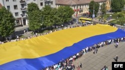 Varios ciudadanos sostienen la bandera de Ucrania, considerada la más grande del mundo, con 60 metros de largo por 40 metros de ancho, en la ciudad de Chernivtsi.