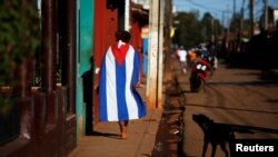 Una persona camina vistiendo una bandera cubana el Alquizar. 