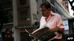 Un hombre lee el periódico en la calle ante la falta de fluido eléctrico en Caracas por tercer día consecutivo.