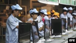 Varias operarias chinas trabajan en una línea de montaje de televisores.
