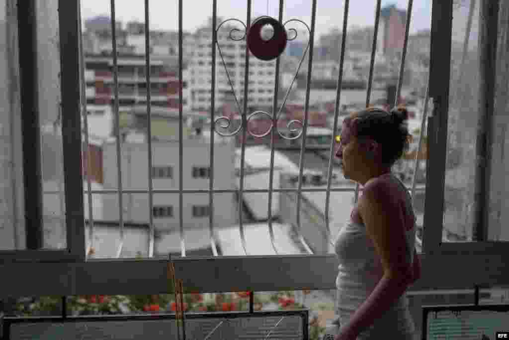 Una mujer se asoma por una ventana de su vivienda cerca de la Plaza Altamira de Caracas (Venezuela). Los vecinos de la céntrica plaza de Chacao viven a diario las consecuencias de los enfrentamientos entre opositores y las fuerzas del orden. 