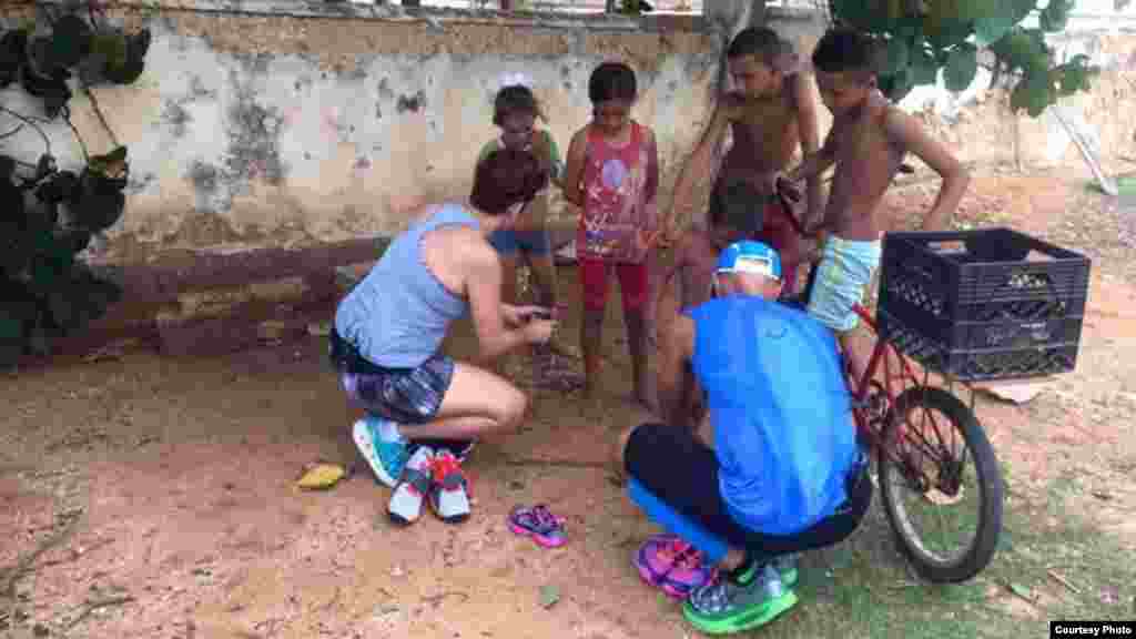 García y su esposa conversan con algunos de los niños a quienes han regalado tenis. Foto tomada del Facebook de Run Across Cuba.