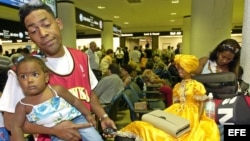 ARCHIVO. Una joven familia de emigrados cubanos esperan noticias sobre su vuelo hacia Cuba.
