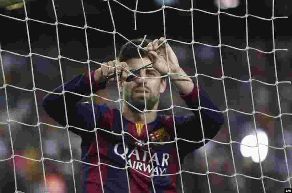 El defensa del FC Barcelona Gerard Piqué corta un trozo de la red de la portería, tras el partido de la final de la Copa del Rey frente al Athletic de Bilbao. Barcelona 3, Bilbao 1.