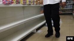 Un hombre camina por un pasillo de supermercado frente a estanterías desabastecidas, en Caracas (Venezuela).