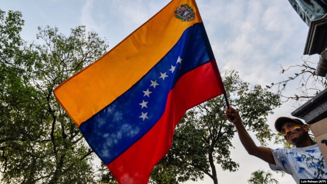 A Venezuelan holds a national flag during a protest against the government of President Nicolas Maduro at Santander square in Cucuta, Colombia, border with Venezuela, on February 12, 2019. - The tug of war between the Venezuelan government and opposition 