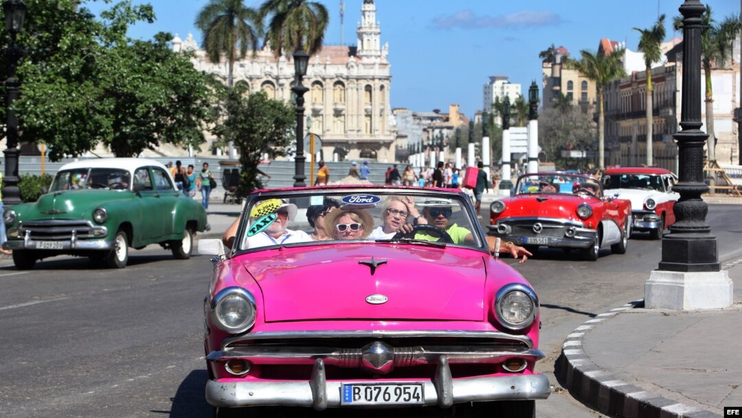 Turistas pasean por La Habana en un auto clásico. 
