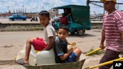 Un hombre transporta recipientes de agua con sus hijos en La Habana, el jueves 28 de mayo de 2026. (Foto AP/Ramón Espinosa)