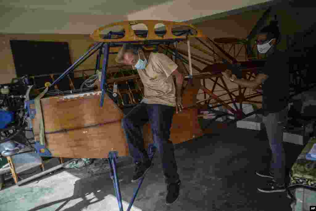 Adolfo Rivera se baja del avión biplaza de madera que está construyendo en el garaje de su edificio de apartamentos en La Habana, Cuba, el viernes 19 de febrero de 2021. (AP Foto/Ramón Espinosa)