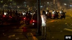 Una mujer hace un llamado a la paz mientras protestantes se enfrentan con miembros de la Guardia Nacional Bolivariana (GNB)