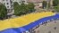 Varios ciudadanos sostienen la bandera de Ucrania, considerada la más grande del mundo, con 60 metros de largo por 40 metros de ancho, en la ciudad de Chernivtsi.