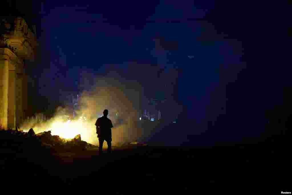Un hombre camina cerca de una pila de basura en llamas tras el colapso de la red eléctrica nacional de Cuba —el tercer apagón importante en nueve días— en La Habana, Cuba, el 14 de julio de 2026. REUTERS/Norlys Perez