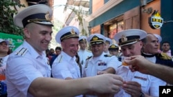 Tripulantes rusos brindan con una bebida tradicional venezolana durante un recorrido de bienvenida por parte de autoridades oficiales en La Guaira, Venezuela, el 2 de julio de 2024. (Foto AP/ Ariana Cubillos)