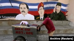 Un vendedor ambulante empuja su carrito junto a un mural con las imágenes de los fallecidos gobernantes Hugo Chávez (C), de Venezuela, y Fidel Castro, de Cuba, junto al presidente de Nicaragua, Daniel Ortega.