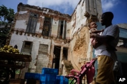 Los residentes pasan por una mansión en ruinas en la calle Villegas en La Habana, Cuba, el jueves 5 de octubre de 2023. (Foto AP/Ramón Espinosa)