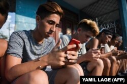 Jóvenes cubanos se conectan a internet en un punto WiFi de La Habana.