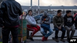 Migrantes esperan a la entrada del Puente Internacional Paso del Norte, en Ciudad Juárez. 