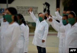 Médicos cubanos alzan sus puños en ceremonia de despedida antes de su partida a Andorra, en marzo pasado. (Yamil Lage/AFP)