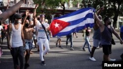 Manifestantes sostienen la bandera cubana durante las protestas del 11 de julio de 2021, en La Habana. (REUTERS / Alexandre Meneghini)