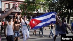 Manifestantes sostienen la bandera cubana durante las protestas en contra del gobierno, en La Habana, el 11 de julio de 2021. (REUTERS / Alexandre Meneghini)