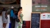 Unos clientes compran en un mercado de La Habana mientras un transeúnte pasa junto a un cartel que muestra los precios de los alimentos, el 17 de octubre de 2026.