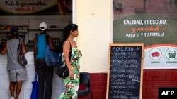 Unos clientes compran en un mercado de La Habana mientras un transeúnte pasa junto a un cartel que muestra los precios de los alimentos, el 17 de octubre de 2026.