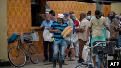 Cubanos hacen colas fuera de las tiendas para hacer compras.