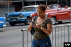 Una mujer usa su teléfono para conectarse a internet en una calle de La Habana.