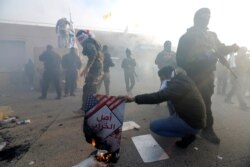 Un manifestante quema un cartel durante una protesta fuera de la puerta principal de la embajada de los Estados Unidos en Bagdad.