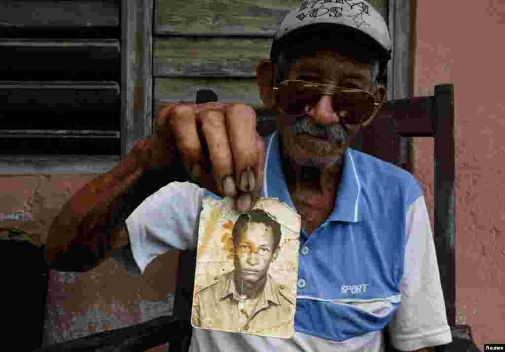 Jesús Alonso, de 87 años y veterano de la Bahía de Cochinos, muestra una fotografía suya en uniforme militar en el portal de su casa en Palpite, Ciénaga de Zapata, Cuba, 7 de abril de 2026. REUTERS/Norlys Pérez