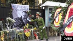 Un policía coloca un cartel con la fotografía de Fidel Castro en la Emabajada de Cuba en Hanoi (Vietnam).