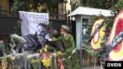 Un policía coloca un cartel con la fotografía de Fidel Castro en la Emabajada de Cuba en Hanoi (Vietnam).