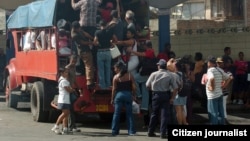 Varias personas intentan subir a un camión particular que funciona como transporte público