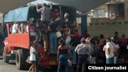Varias personas intentan subir a un camión particular que funciona como transporte público