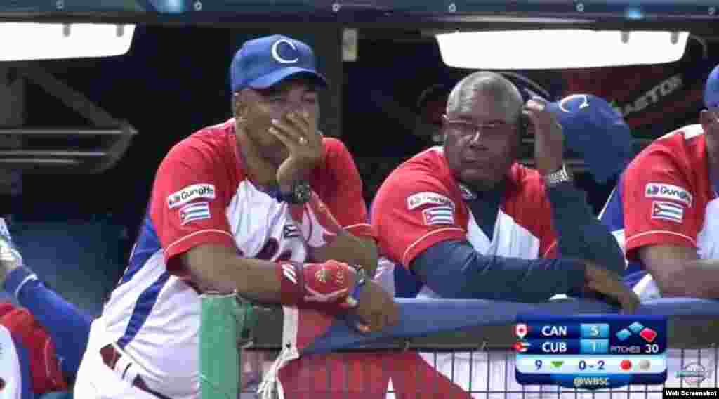 El mentor del equipo Cuba, Víctor Mesa (i), observa cómo son retirados sus peloteros en la novena entrada.