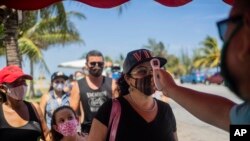 Varias personas hacen fila el lunes 10 de agosto de 2020 para que les tomen la temperatura con el fin de saber si están infectadas con el coronavirus, en un retén de la policía en la provincia de La Habana, Cuba. (AP Foto/Ramón Espinosa)
