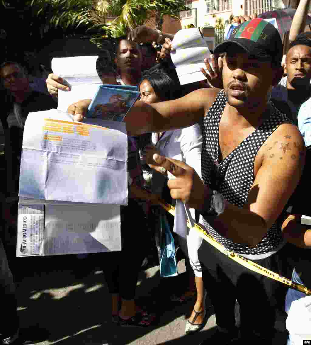 Un hombre, con un pasaporte en su mano y algunos documentos que confirman sus planes de viaje, protesta frente a la embajada de Ecuador en La Habana.