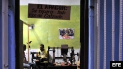 Un zapatero mantiene su taller privado abierto hasta la noche.