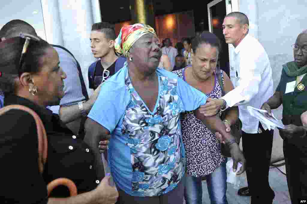 Una mujer, a punto del desmayo, es asistida por sus allegados en La Habana a la muerte del dictador Fidel Castro.