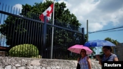 Cubanos caminan frente a la embajada de Canadá en La Habana.